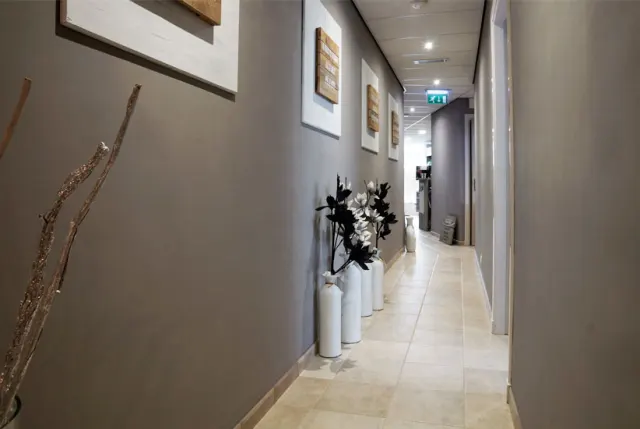 De gang van de salon, met lijsten aan de muur en witte vazen met bloesem