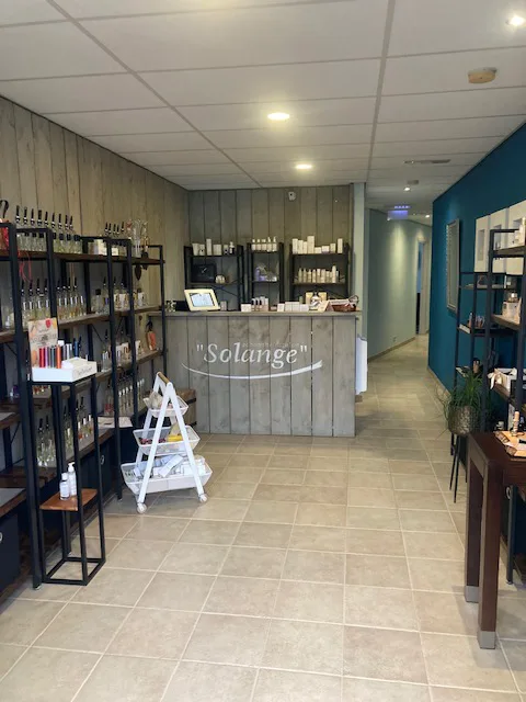 De ontvangstruimte van Schoonheidssalon Solange, met de houten balie en de schappen van het winkeltje